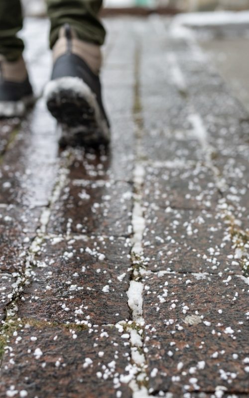 Selective,Focus,On,Technical,Salt,Grains,On,Icy,Sidewalk,Surface Selective focus on technical salt grains on icy sidewalk surface in wintertime, used for melting ice and snow. Applying salt to keep roads clear and people safe in winter weather from ice or snow